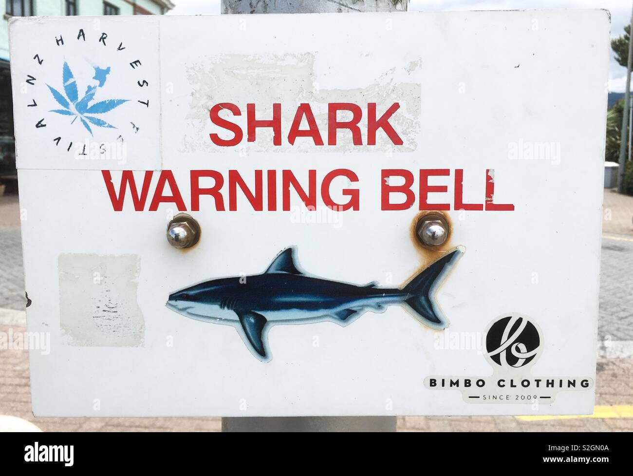 Shark warning bell sign on post holding hand bell at St Clair’s beach, Dunedin, New Zealand. Stock Photo