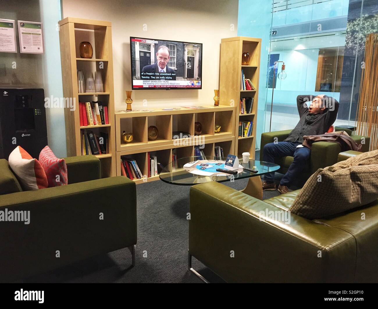 A man relaxes in a breakout area at work. - Smartphone Captured Stock Image