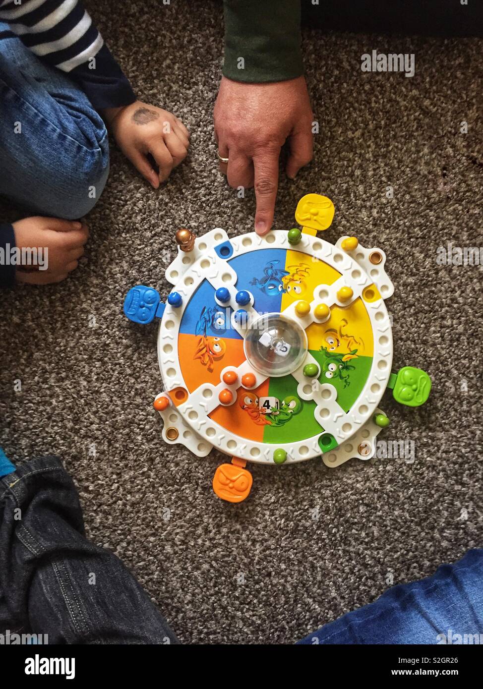 A family play the board game ‘Frustration’ on the floor. Stock Photo