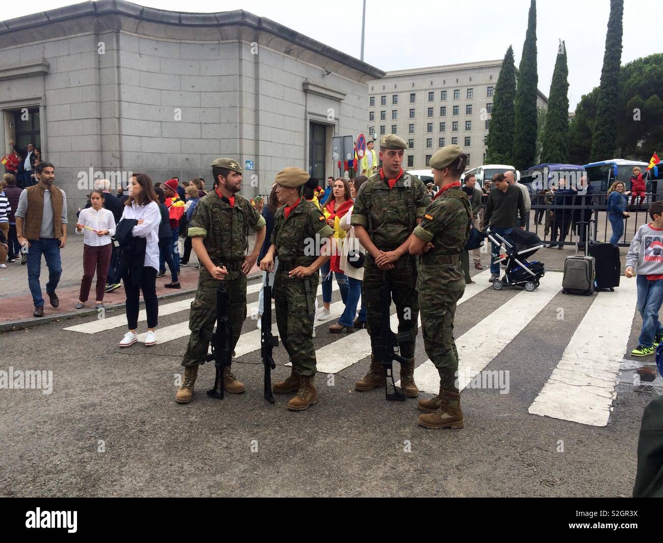Spanish military soldiers or personnel chatting in a group of four while on duty in the streets of Madrid in Spain during Spanish national day celebrations - Smartphone Captured Stock Image