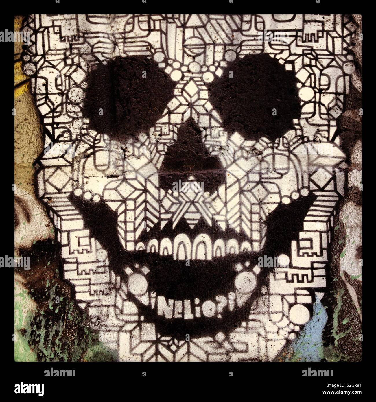 A closeup of an intricate black and white geometric design street art graffiti skull painted on a wall Stock Photo