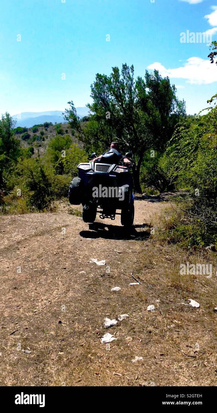 Guy wheeling at hills with quad bike Stock Photo
