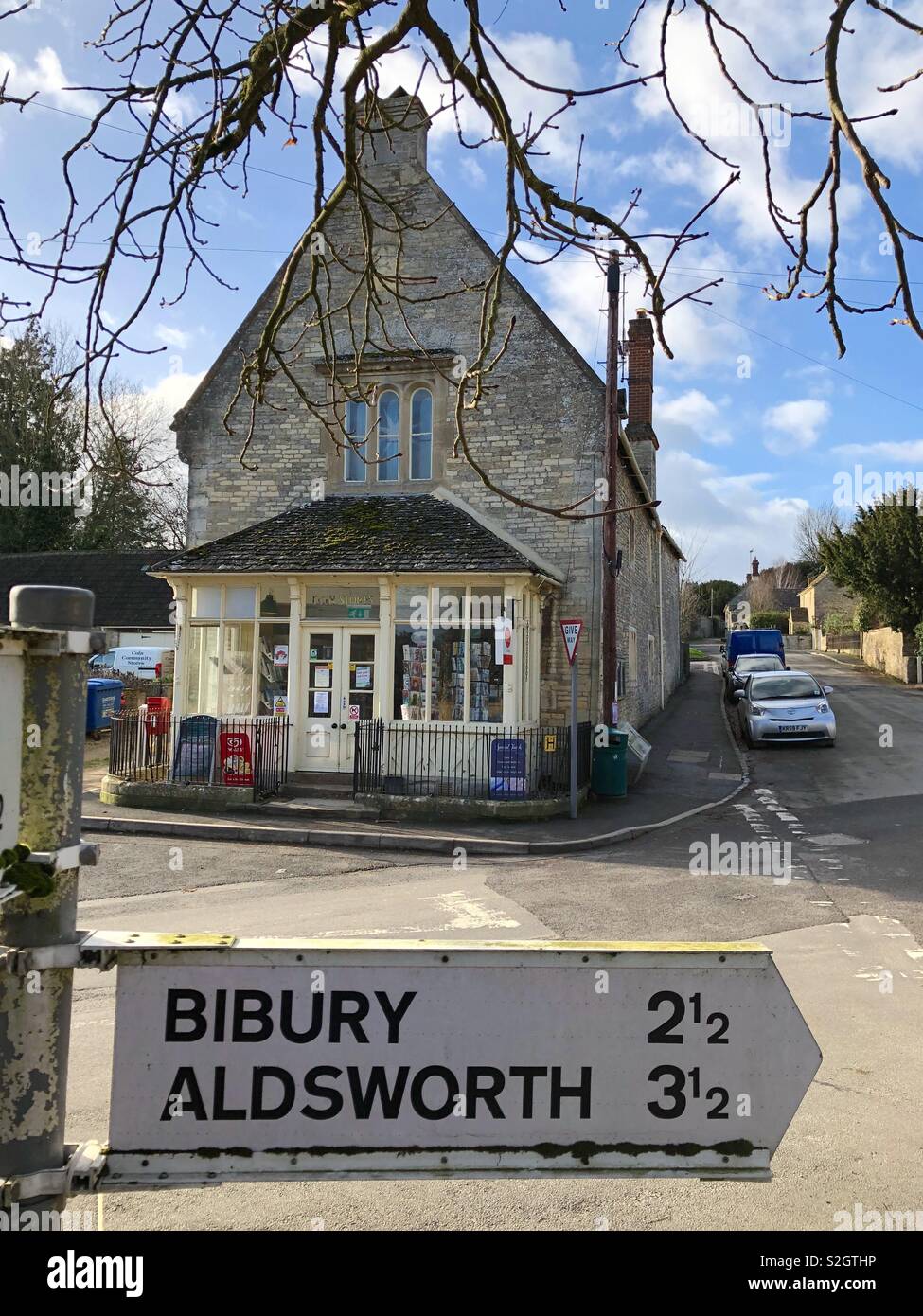 Traditional Cotswold village shop seen over a traditional signpost to local villages, now a rare sight. - Smartphone Captured Stock Image