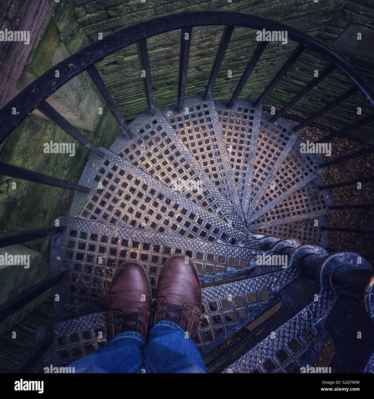 Man standing at the top of a metal spiral staircase. - Smartphone Captured Stock Image