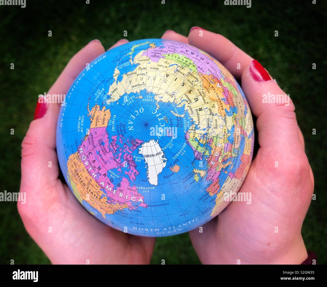 The “world” held in the hands of a young woman. - Smartphone Captured Stock Image