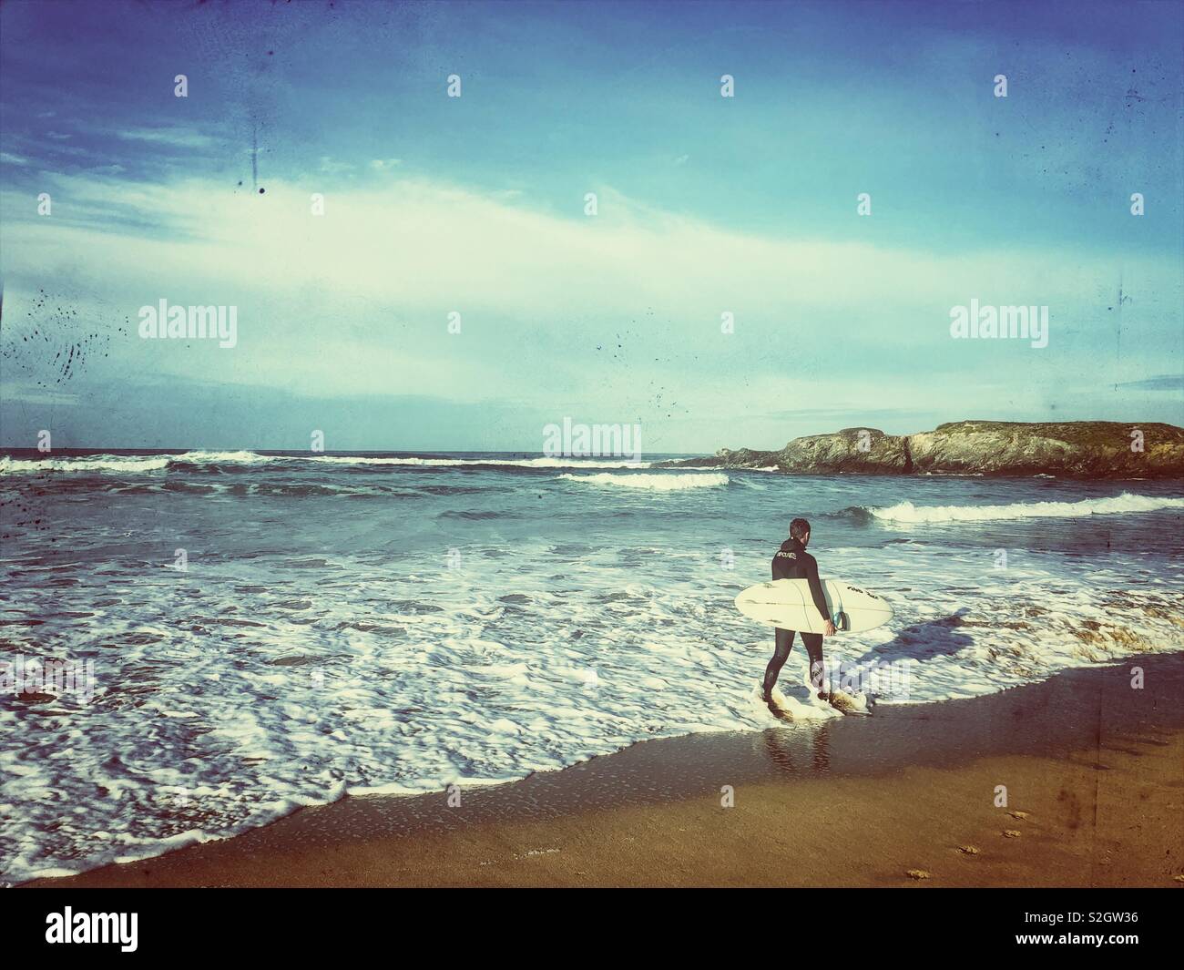 Surfer walking along the surf line, Constantine Bay, North Cornwall, early November. - Smartphone Captured Stock Image