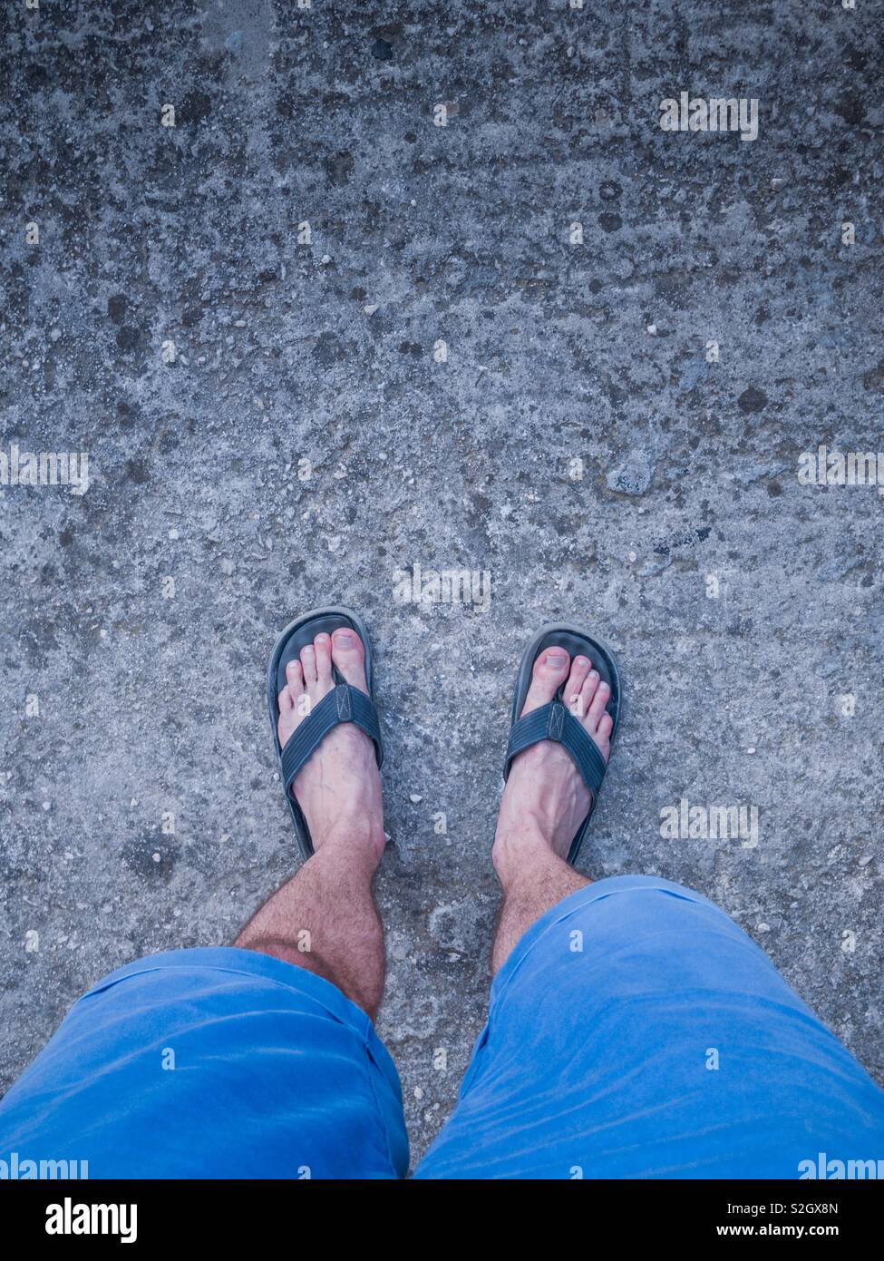 Man wearing blue shorts and flip flops top view Stock Photo