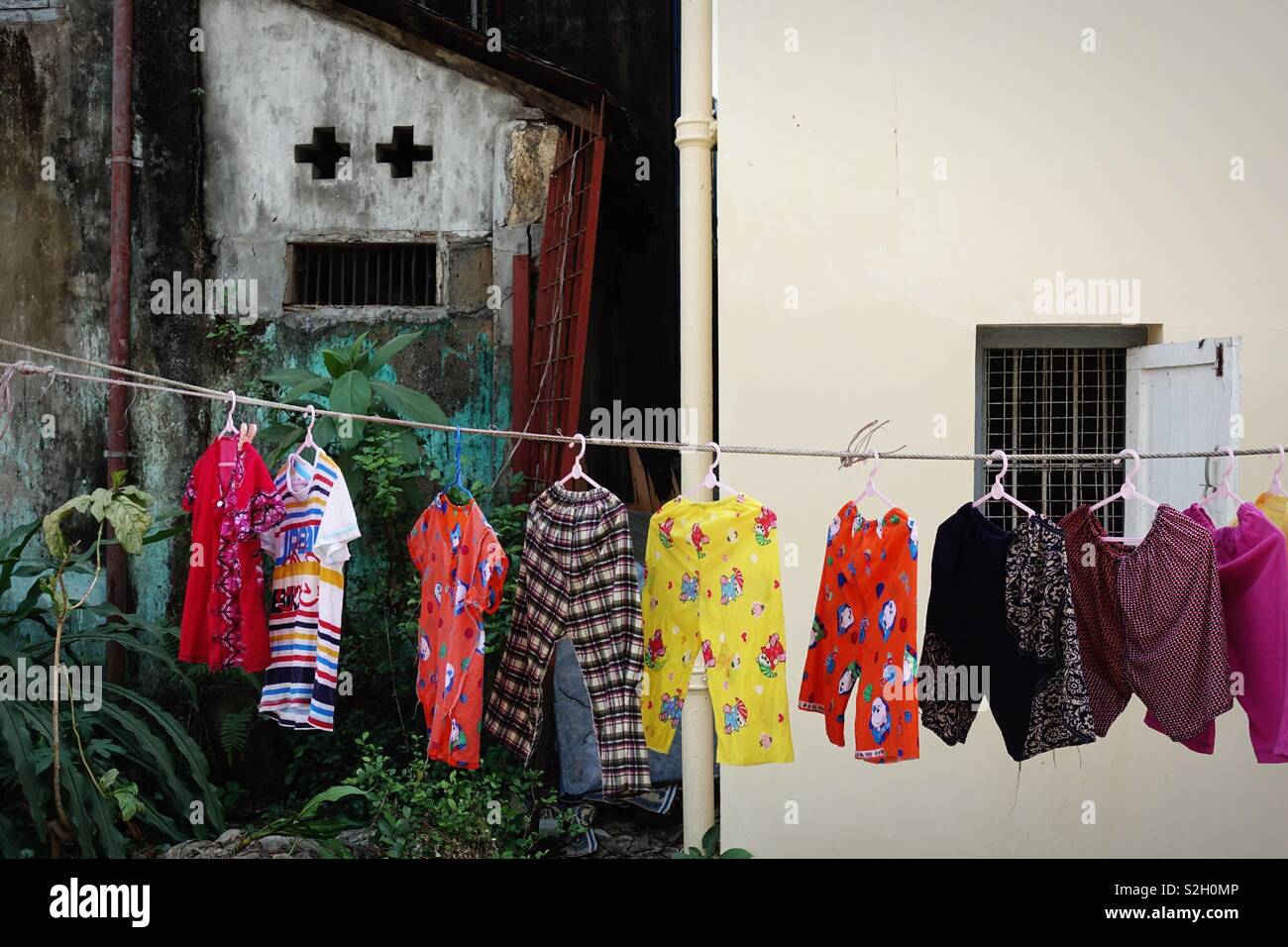 Fresh washed clothes on a clothes line drying in the sun in front of a funny  faced house Stock Photo - Alamy