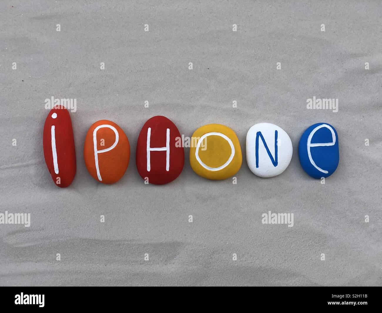 Iphone text with multi coloredsl stones over white sand Stock Photo