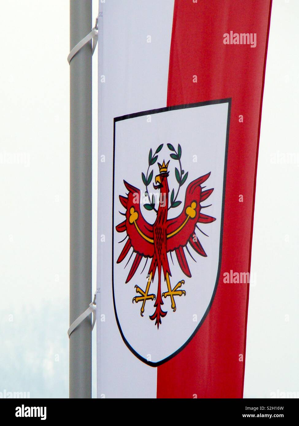 The coat of arms on the red white flag of Tyrol in Austria shows a red  eagle with golden crown and green wreath Stock Photo - Alamy