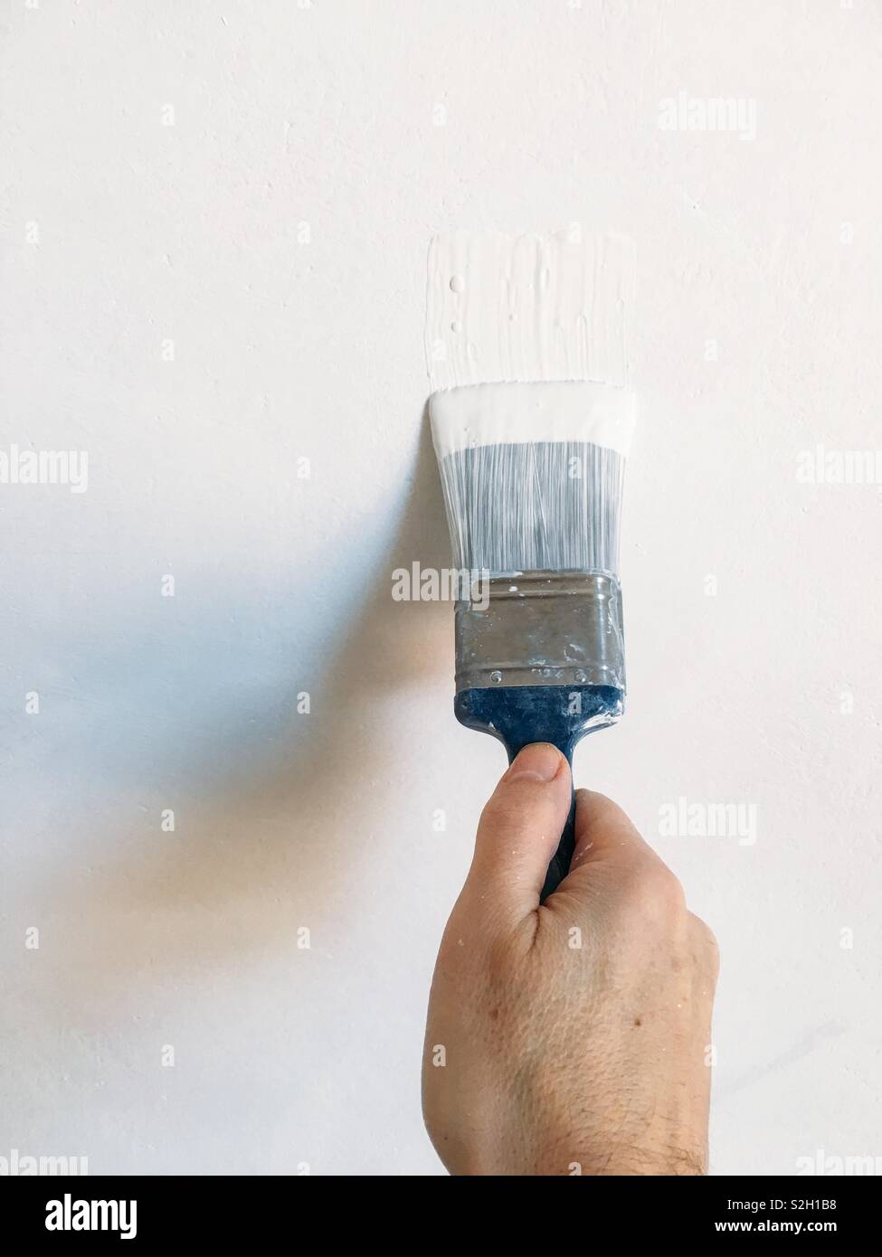 Male hand paint a wall white Stock Photo