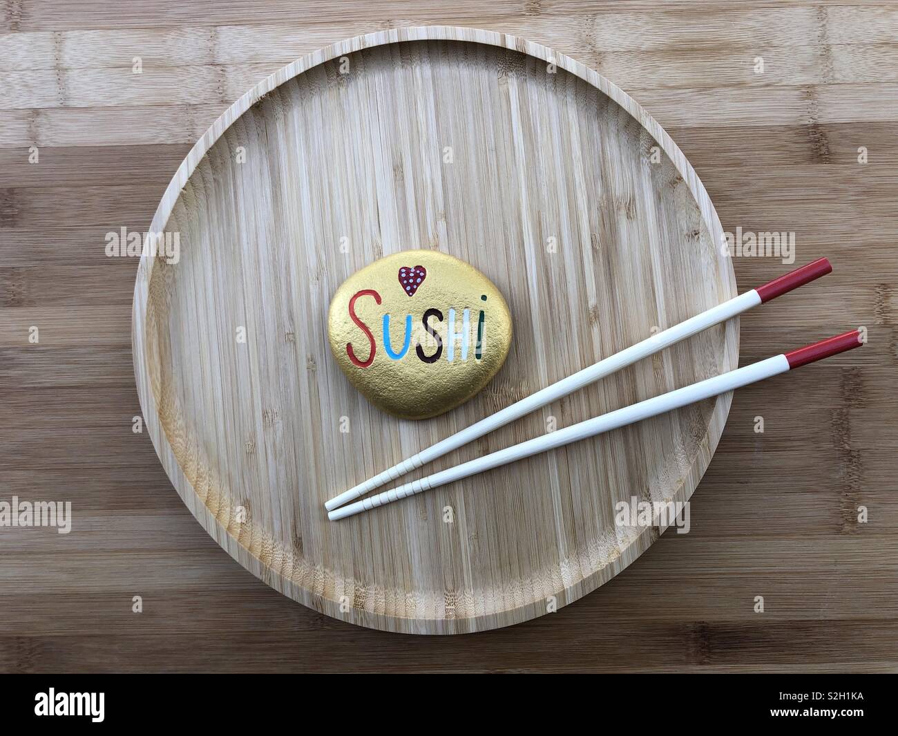 Sushi concept with a painted stone in a wooden dish and two chinese sticks - Smartphone Captured Stock Image
