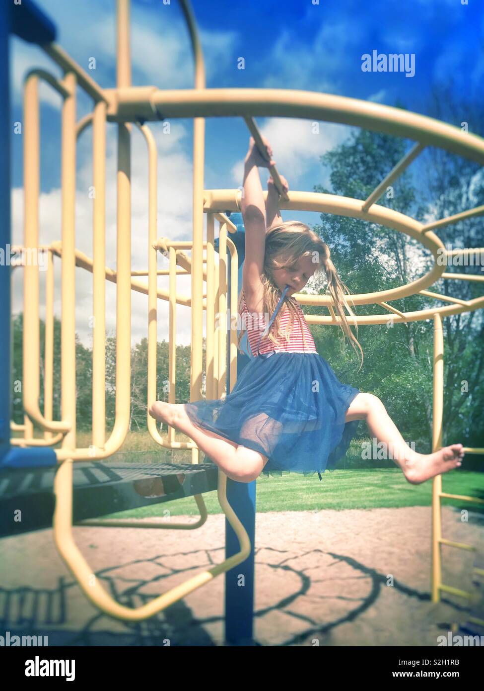 Image Of Young Girl Playing On Monkey Bars At The Park