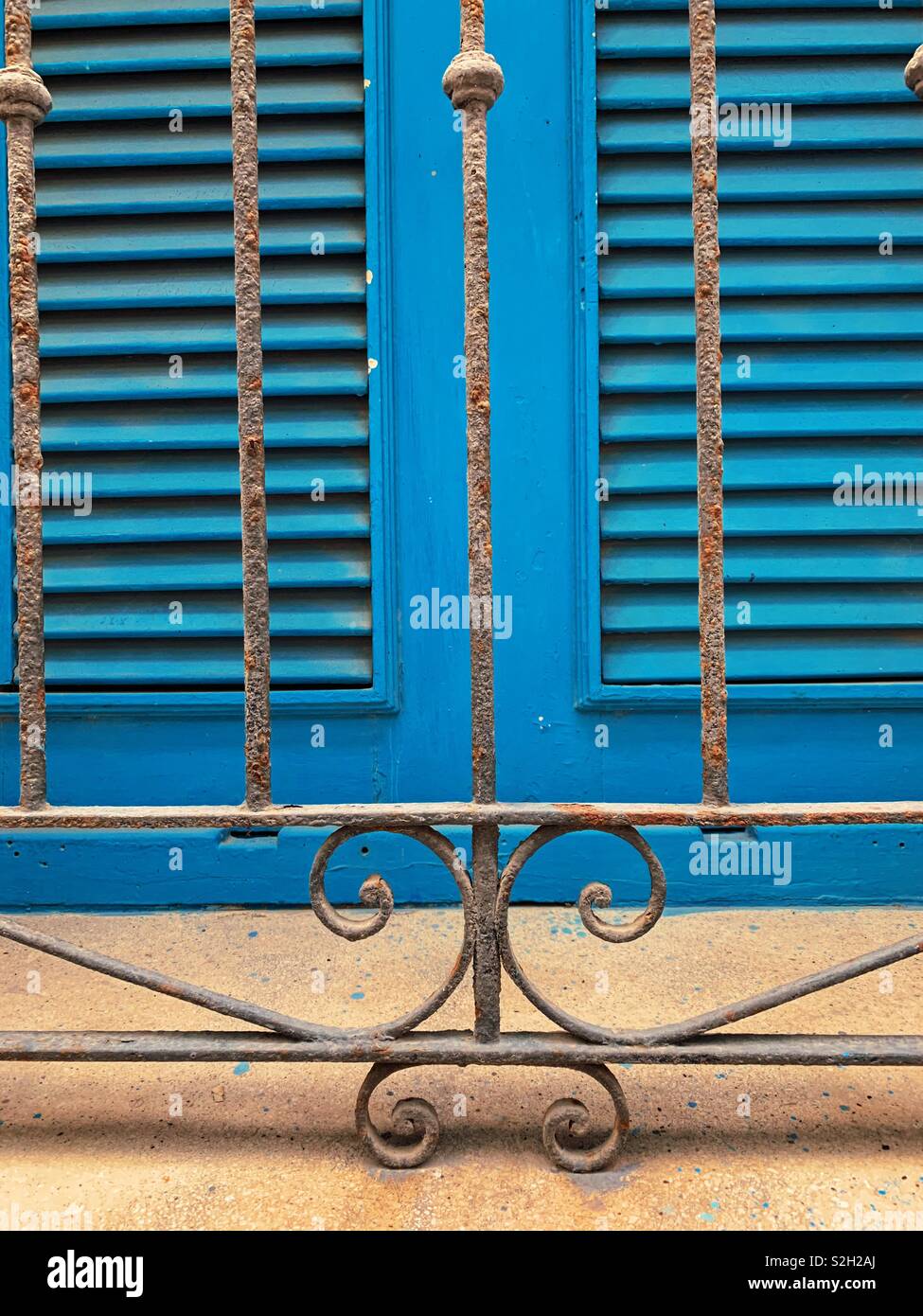 Decorative rusted window bars in front of blue exterior shutters in old Havana Cuba Stock Photo