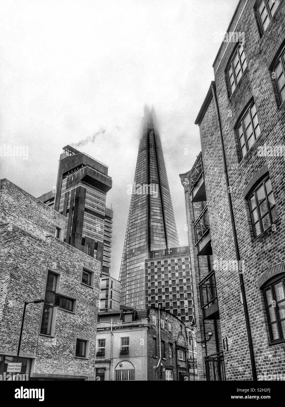 The mist shrouded Shard building in London, England seen from a backstreet near London Bridge Stock Photo