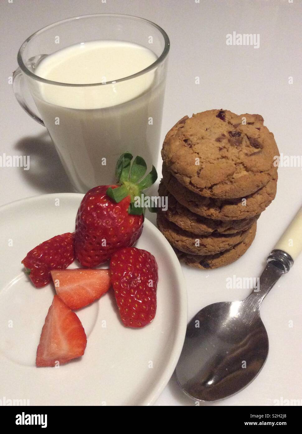 Breakfast with a glass of milk, fresh strawberries, homemade cranberry and chocolate cookies Stock Photo