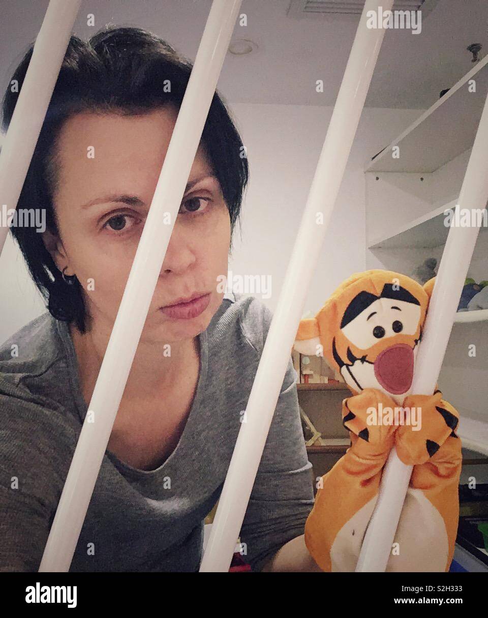 A woman behind a bars playing prisoner with a puppet. Stock Photo