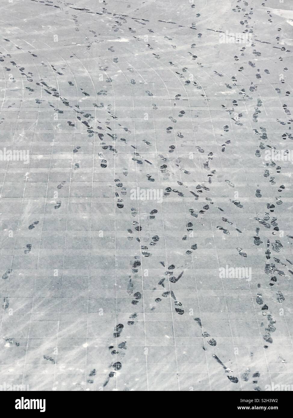 A mess of footprints leading back and forth through a light dusting of snow. - Smartphone Captured Stock Image