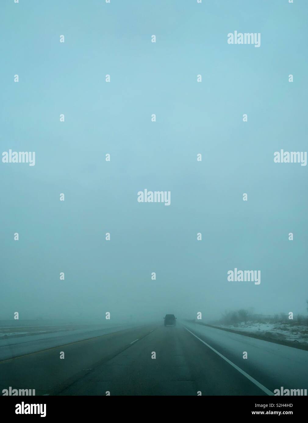 One car driving on a foggy road. - Smartphone Captured Stock Image