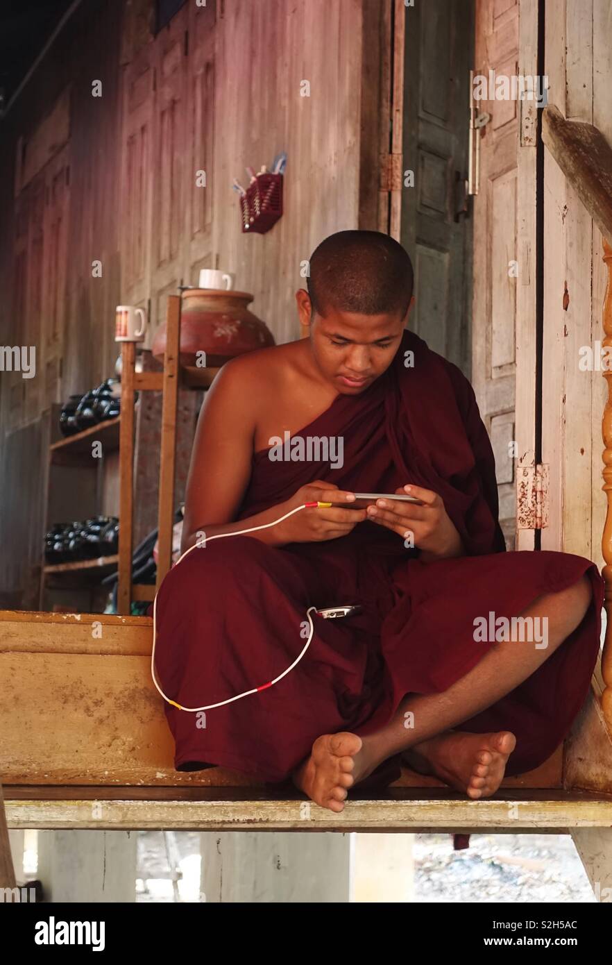 Buddhist monk gaming on his mobile device Stock Photo