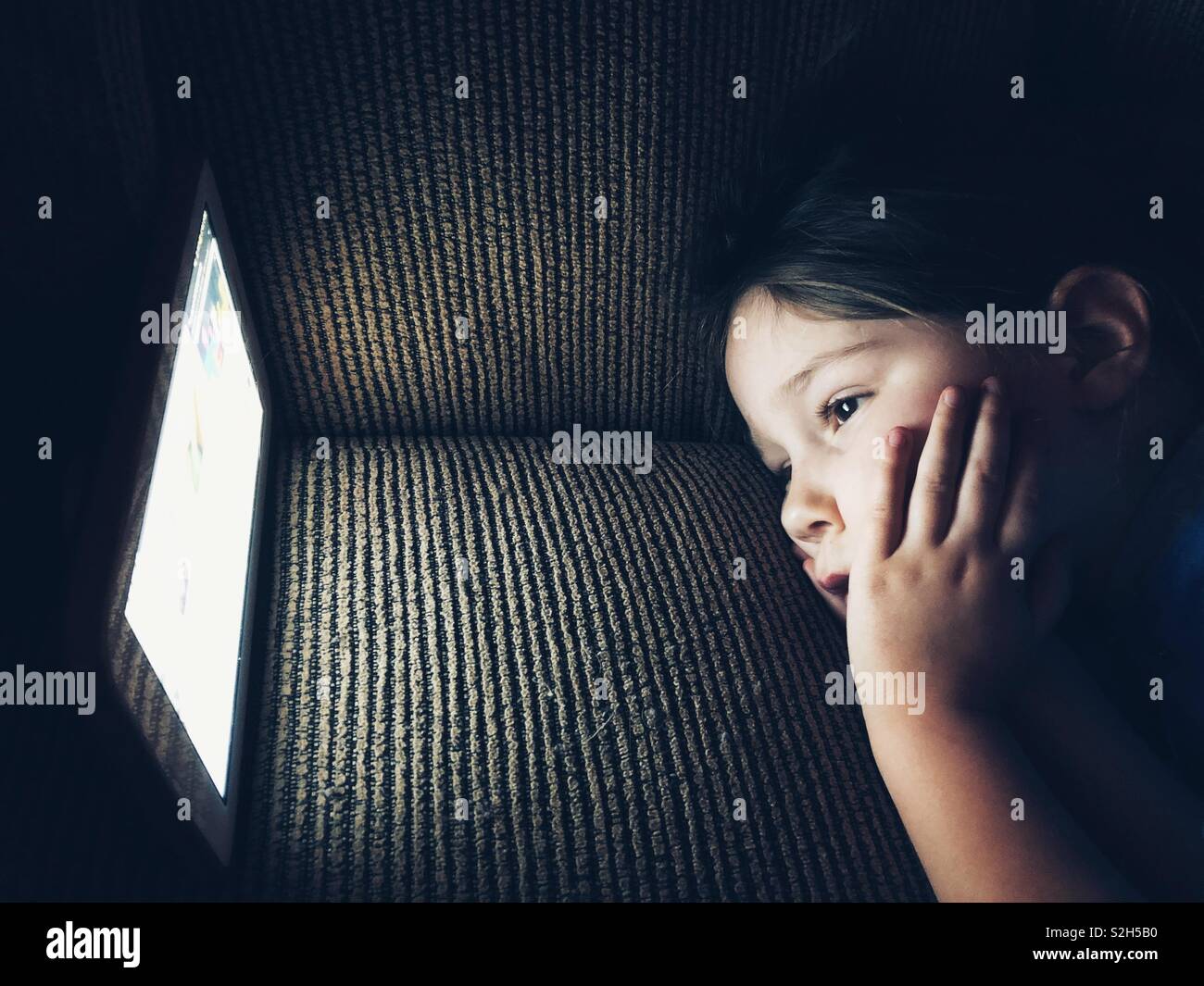 Young child looking at tablet screen in the dark Stock Photo