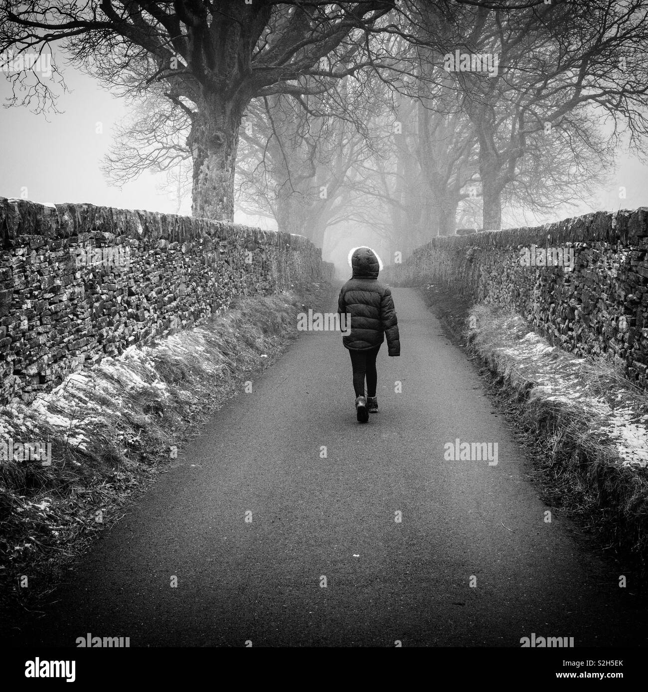 Middle of the road.... girl walking down a country lane. Stock Photo