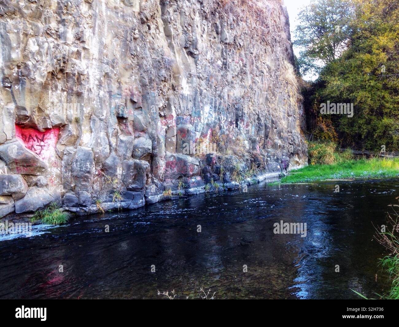 Rock wall covered in graffiti beside river in Eastern Washington state - Smartphone Captured Stock Image