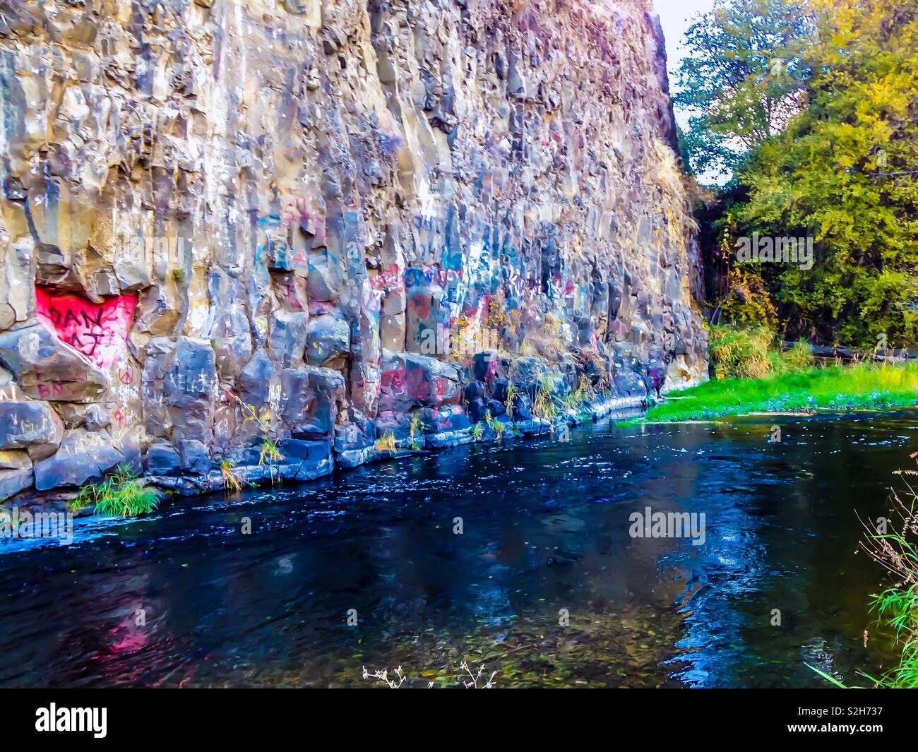 Colorful graffiti covers rock wall beside river 'swimming hole' in Eastern Washington state - Smartphone Captured Stock Image