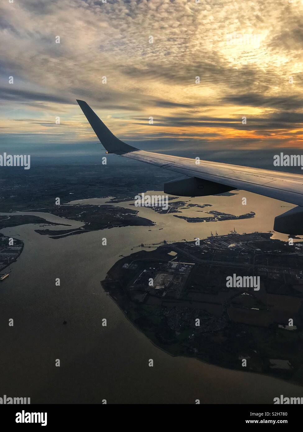 Dramatic sky and sunset on approach to London City Airport over the English Channel. Stock Photo