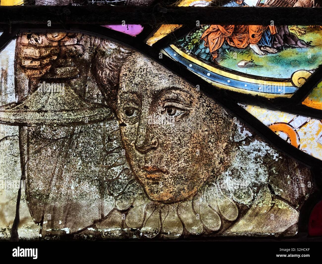 16th Century stained glass with a stylish depiction of an Elizabethan or Tudor woman with an solemn expression and holding a cup or chalice. - Smartphone Captured Stock Image
