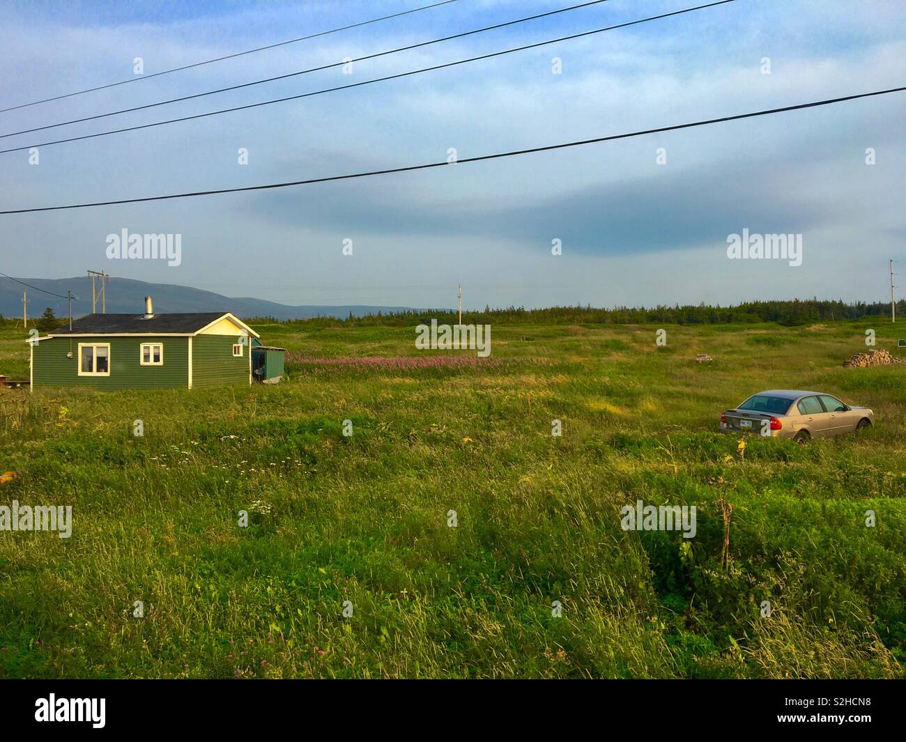 Rural area of Sally’s Cove with one house and car in long grass - Smartphone Captured Stock Image
