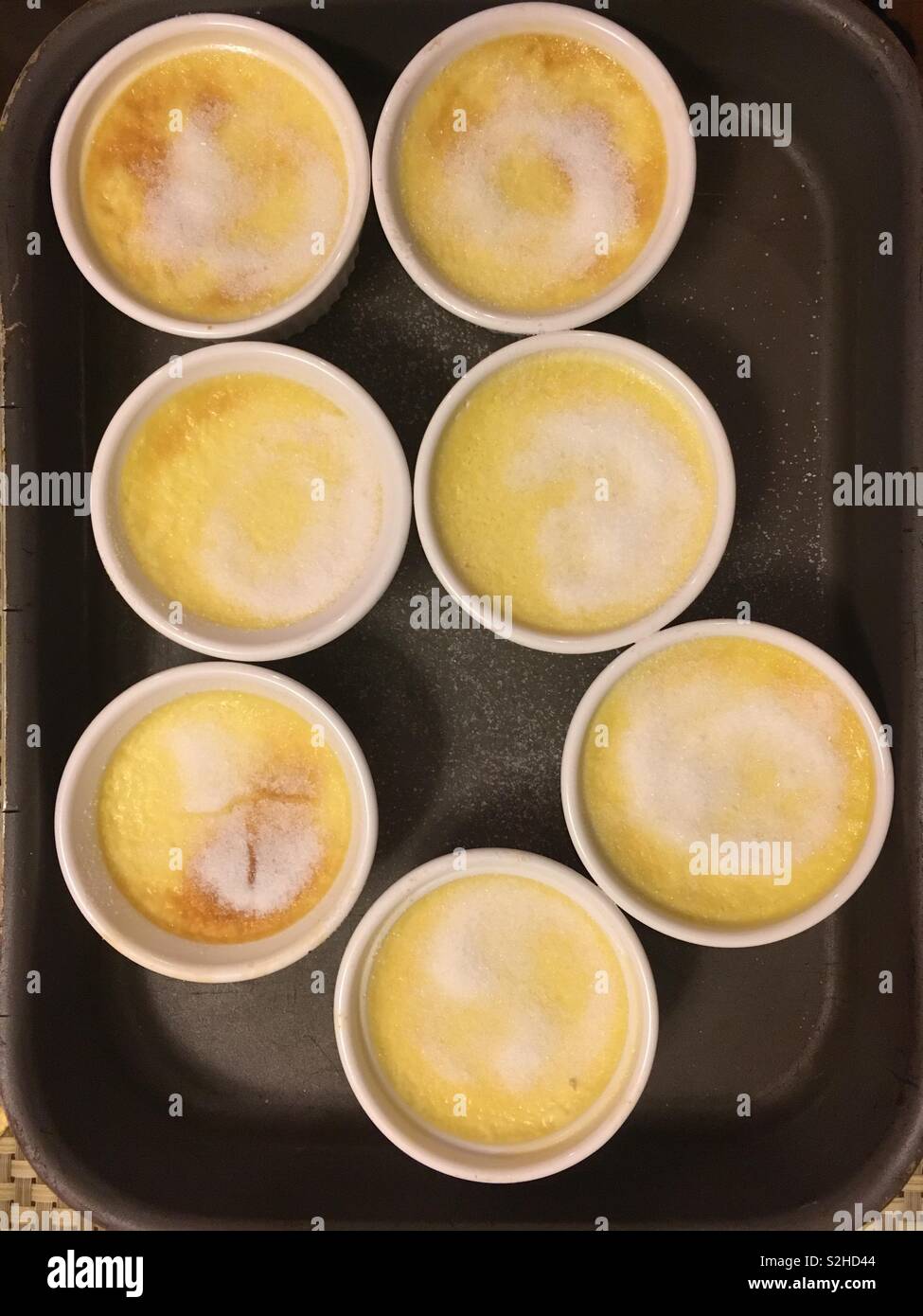 Grandma’s homemade creme brûlée dessert in the little white bowls ready to be torched. Stock Photo