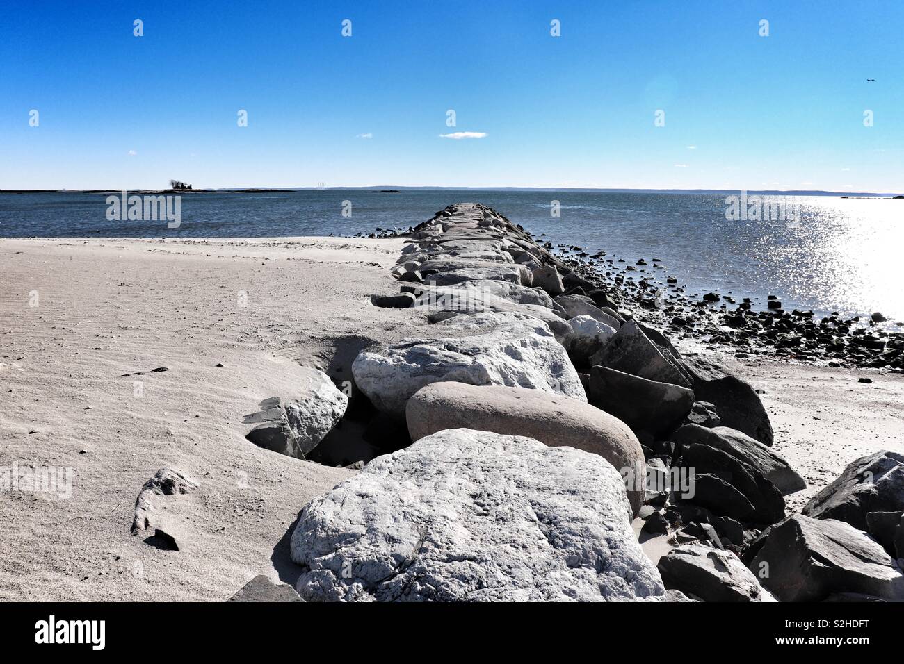 Rocks forming a sandbreak on the beach Stock Photo