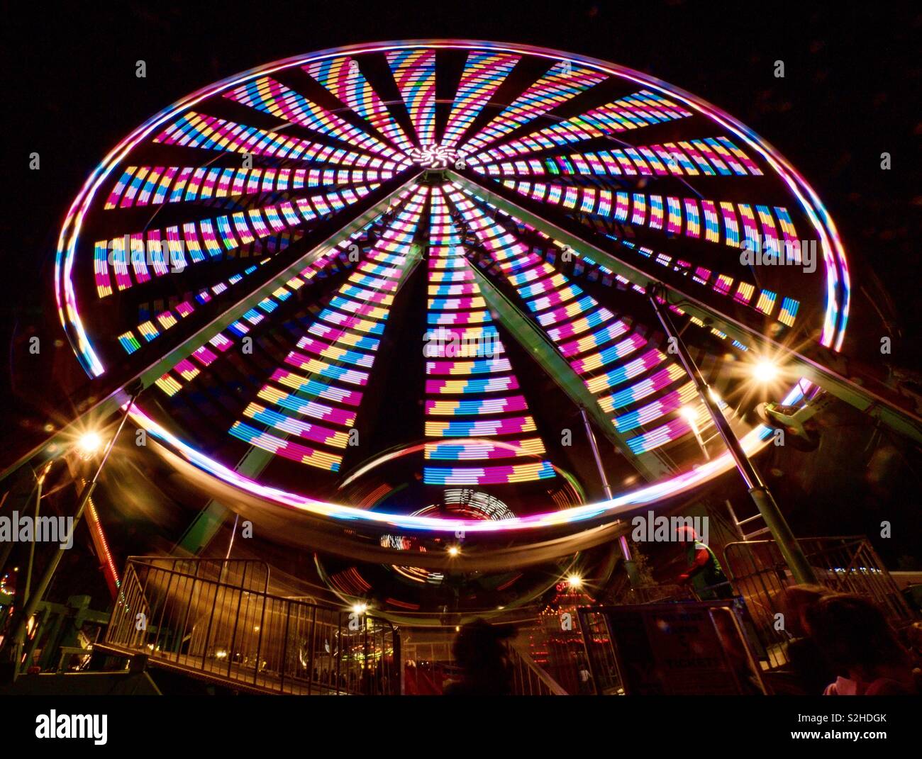 Ferris wheel at town fair creates candy colored pinwheel Stock Photo