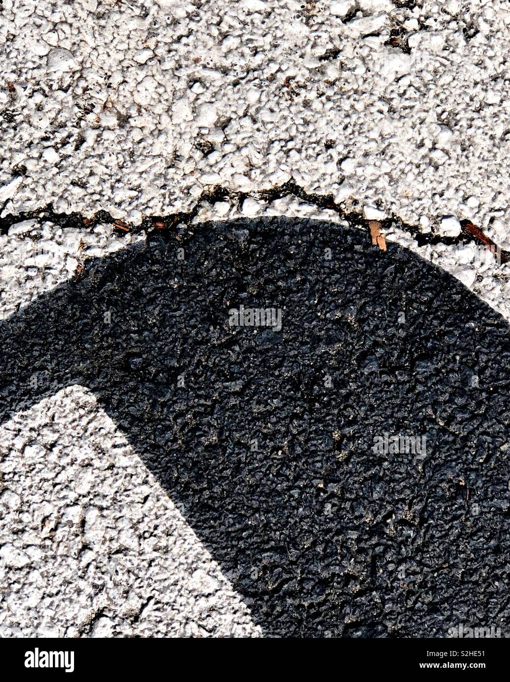 Close up asphalt-level parking directions create an urban abstraction. It’s a minimal take on urban decay and the city fighting a losing battle against it. Stock Photo