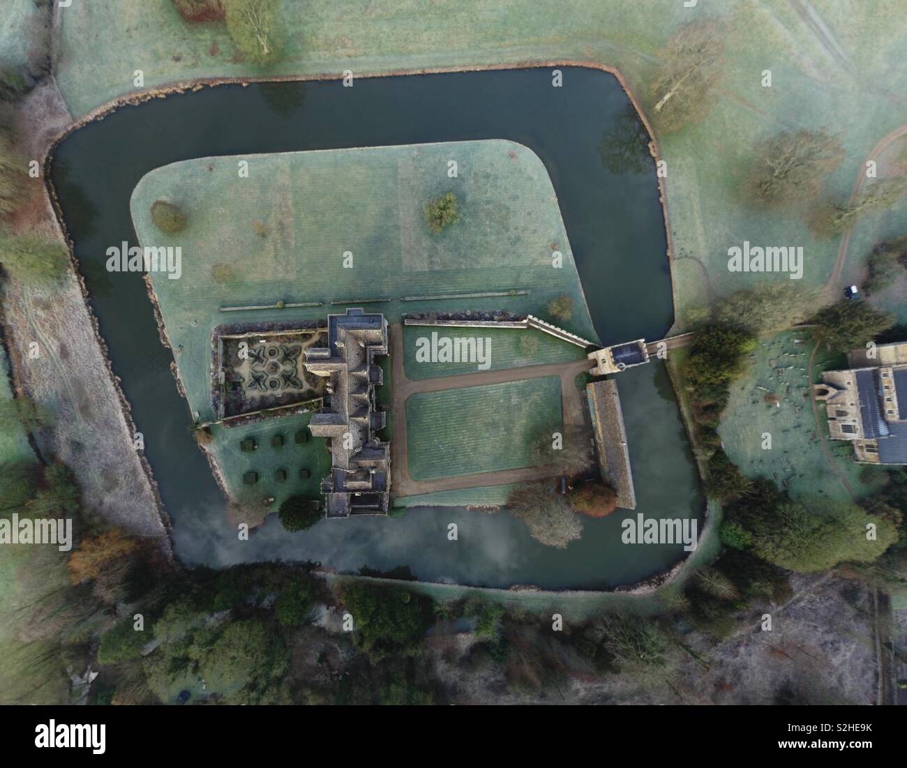 Vertical aerial view of Broughton Castle and Moat, with Broughton Church, with frost and ice, from 400 feet. - Smartphone Captured Stock Image