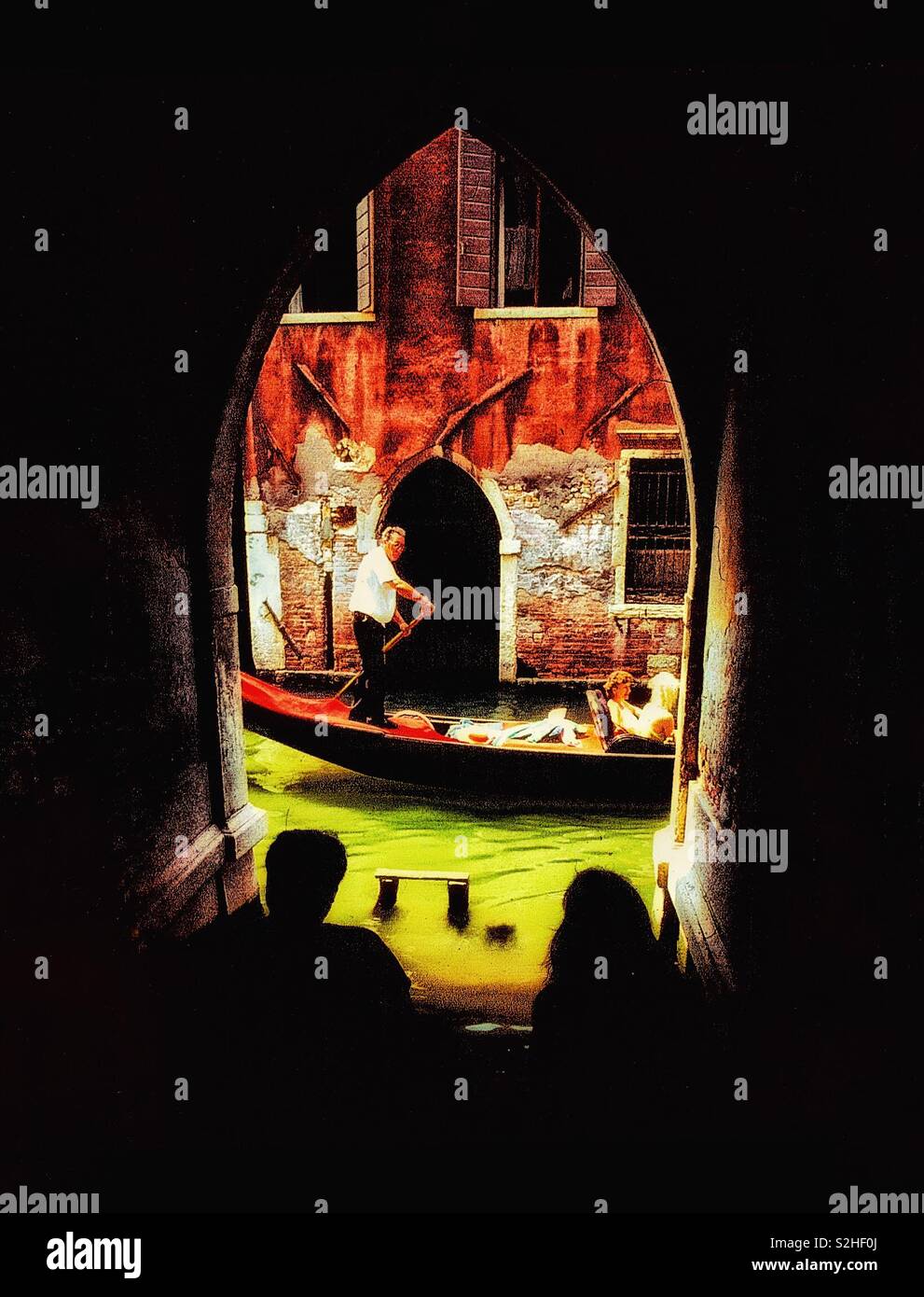 A couple watching a gondola on a canal in Venice. - Smartphone Captured Stock Image