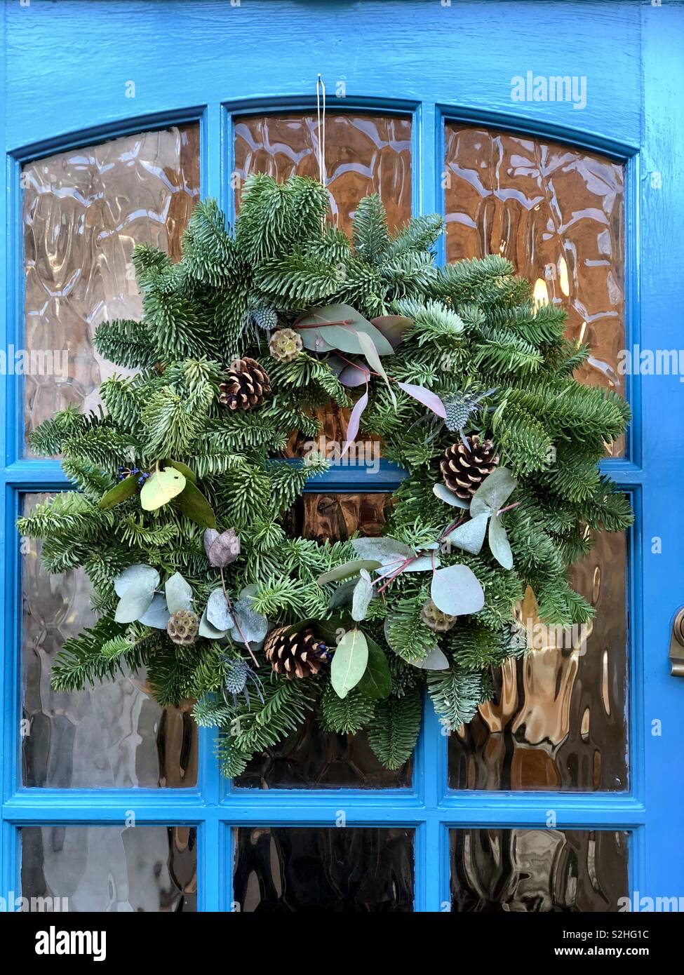 Christmas wreath on blue front door in close up - Smartphone Captured Stock Image