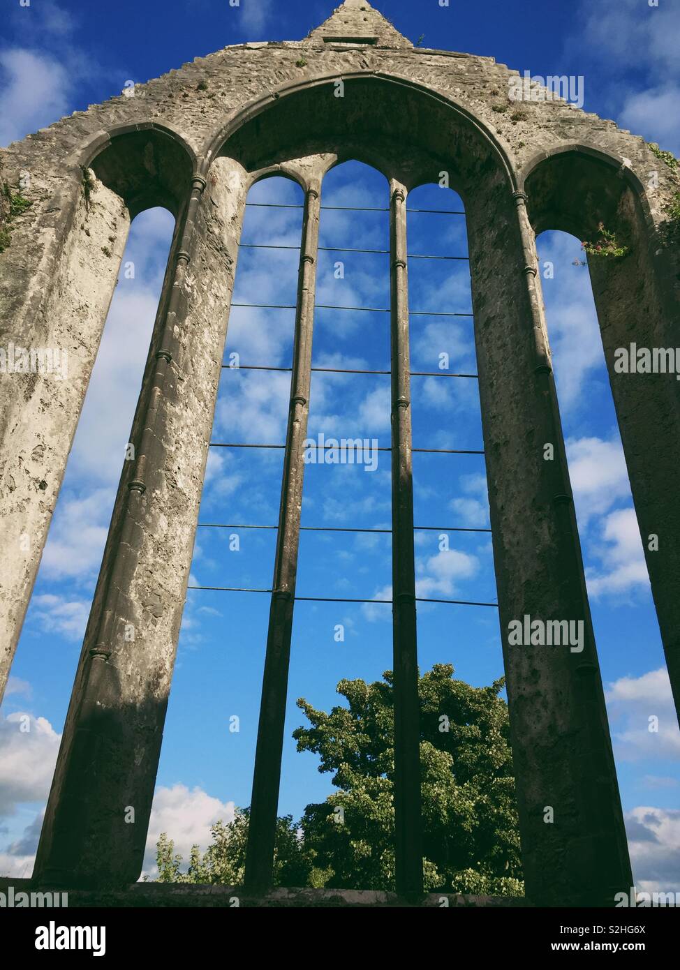 View through Ennis friary ruins to blue sky and trees in Ireland - Smartphone Captured Stock Image