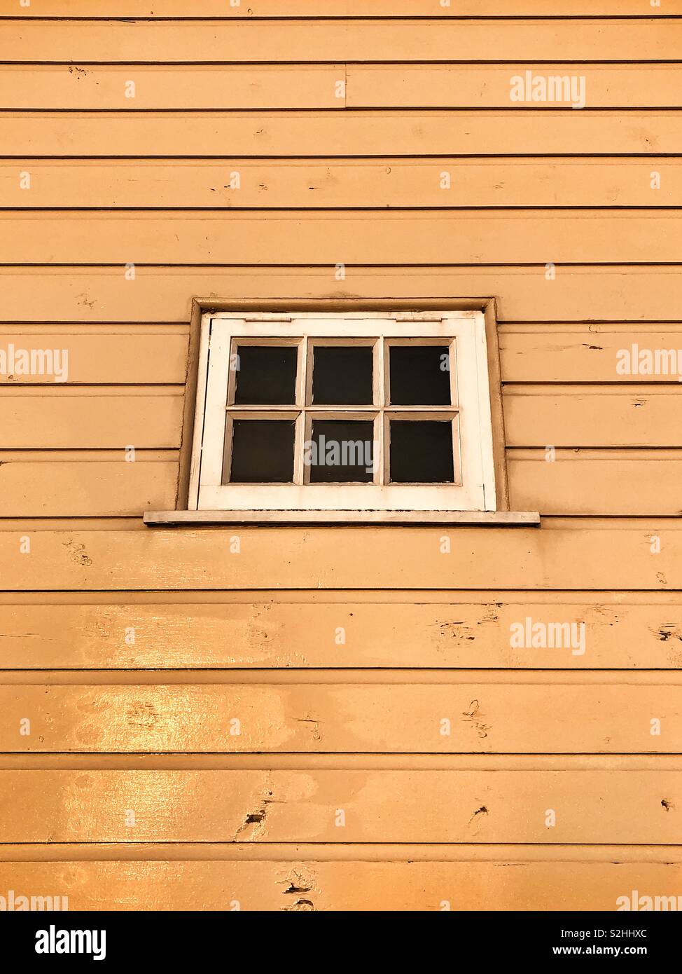 Small window in a wooden building lit by morning sunlight. Stock Photo