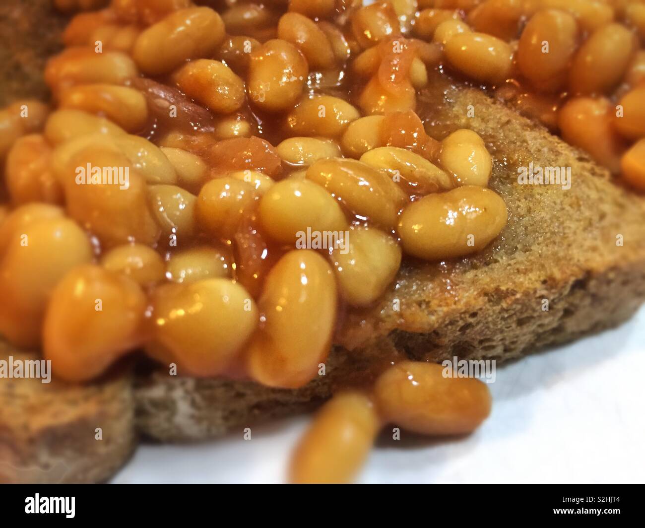 Baked beans on toast easy meal to cook and prepare.  Quick food for busy lifestyle.  Best served with toast. Stock Photo