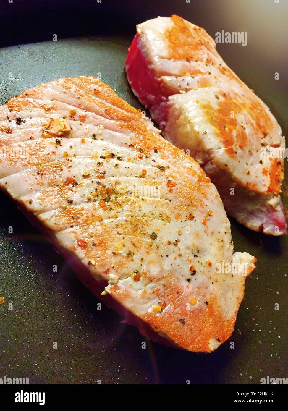 Fresh tuna steaks being seared in a hot skillet. - Smartphone Captured Stock Image