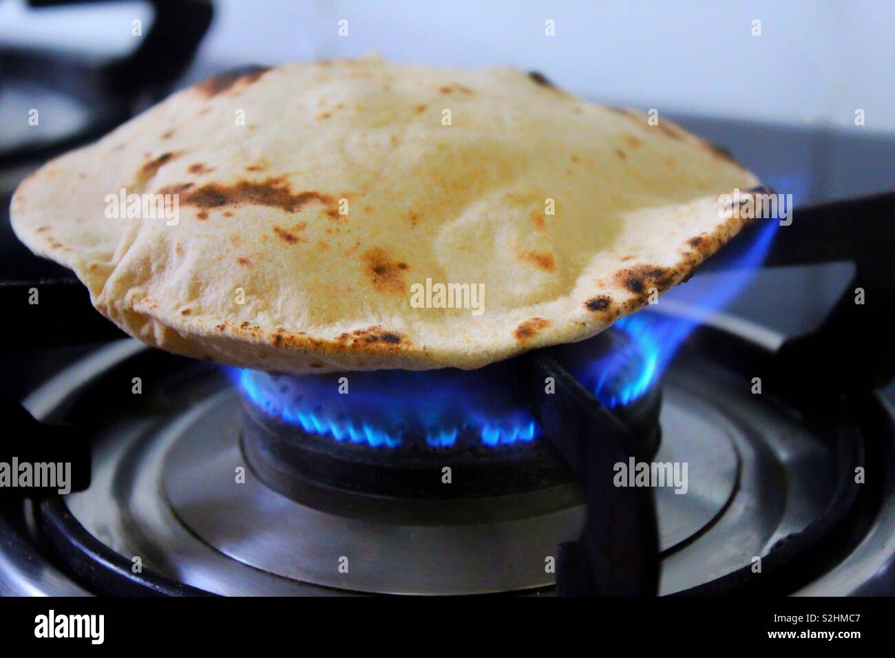 An Indian roti or tortilla on a gas stove being cooked Stock Photo