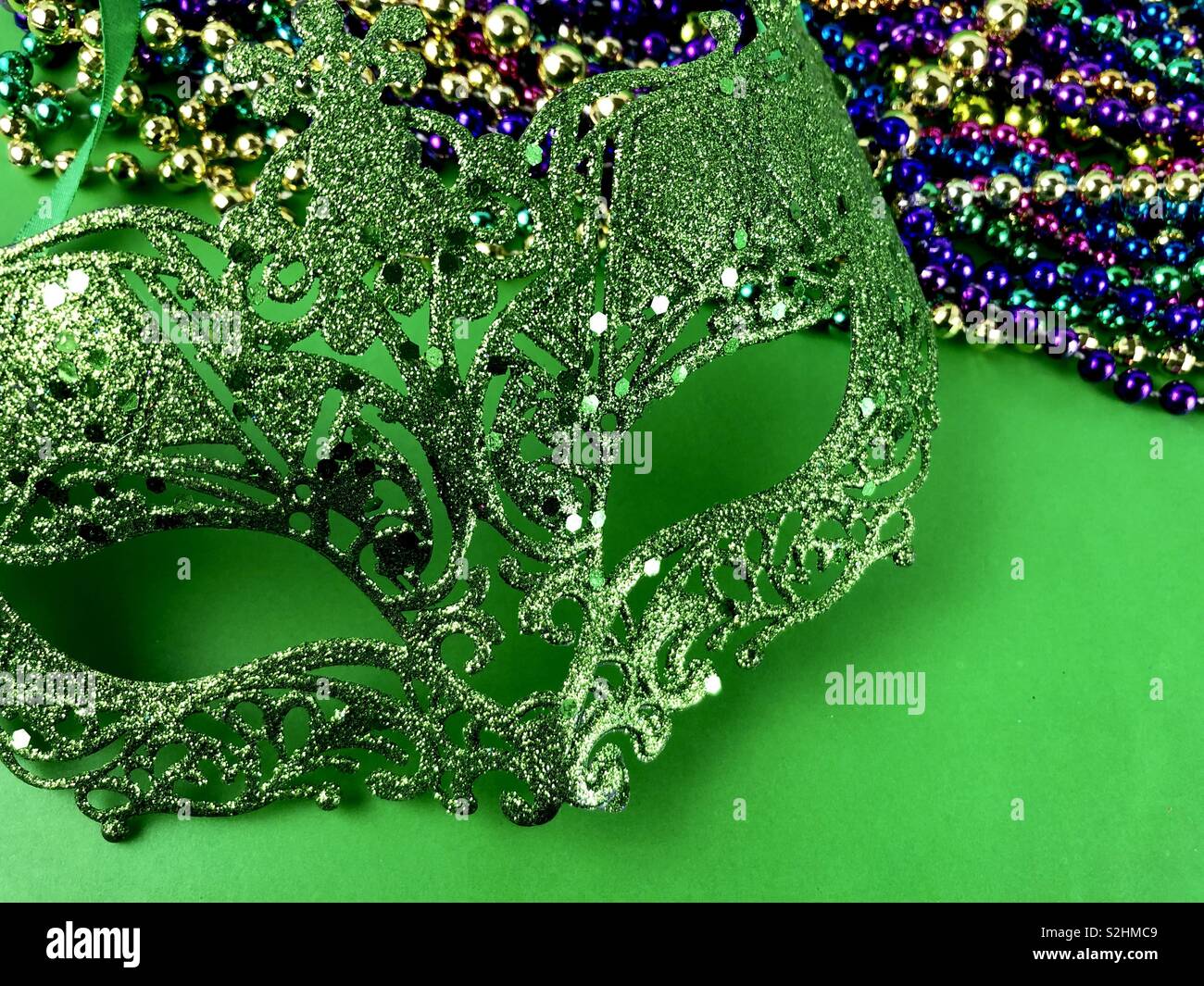 Mardi Gras mask and beads on a green background Stock Photo - Alamy