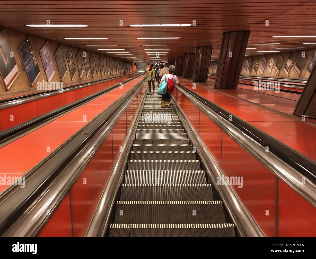 Budapest, Hungary - June 14, 2017: Public transit riders descend down a steep escalator to the Kalvin Ter Line 3 Station. - Smartphone Captured Stock Image