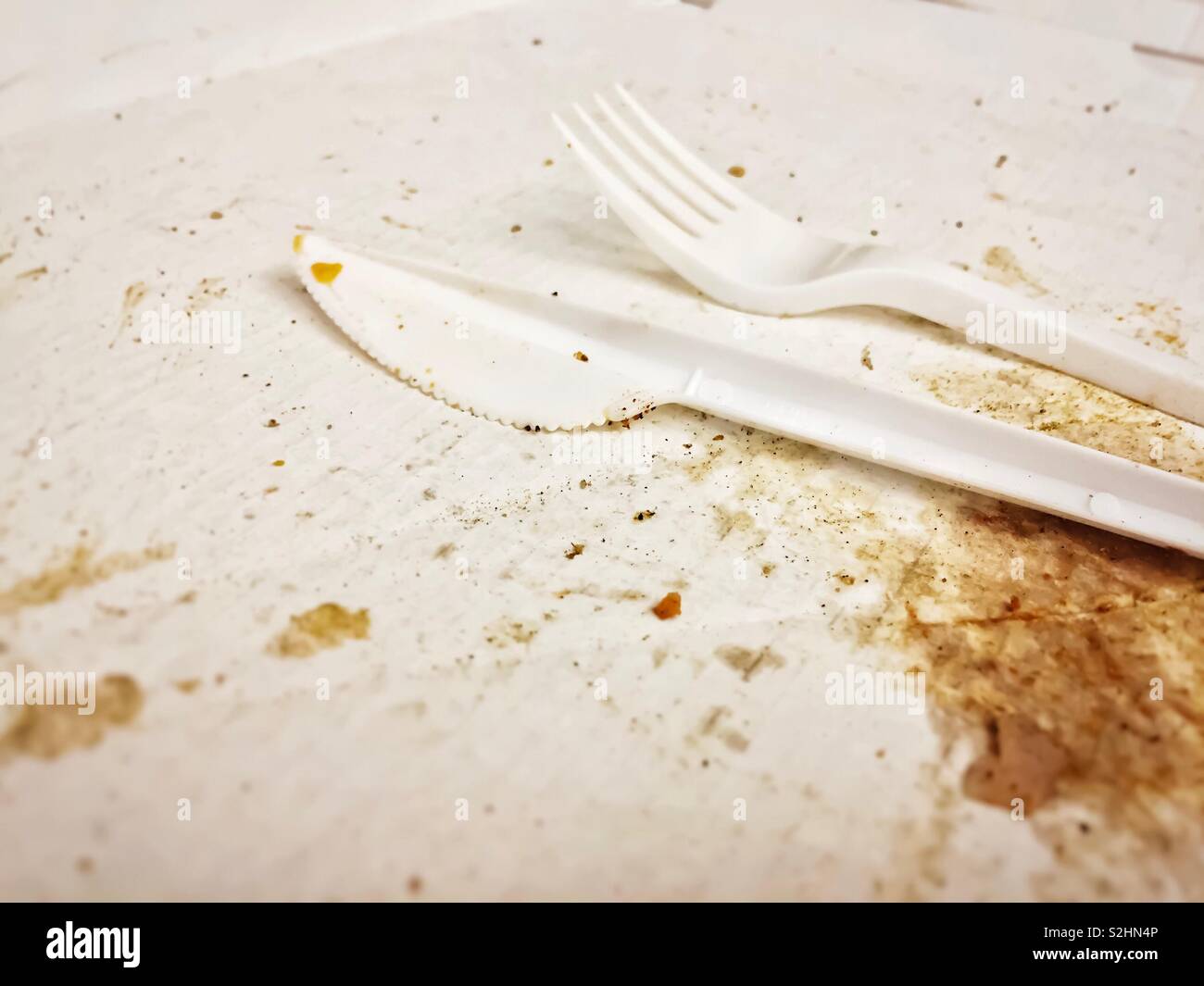 Disposable white plastic cutlery on a dirty pizza cardboard box after eating - Smartphone Captured Stock Image