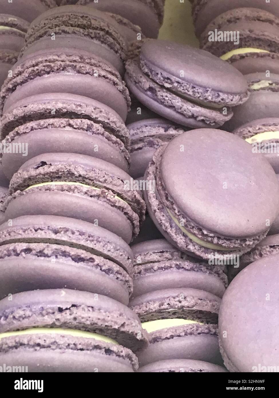 Dish full of light purple macaron cookies with white cream cookie filling as a tasty treat and delicious dessert. Stock Photo