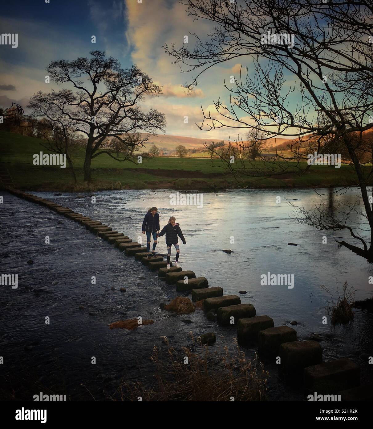 Two girls on stepping stones at Whitewell in Lancashire - Smartphone Captured Stock Image