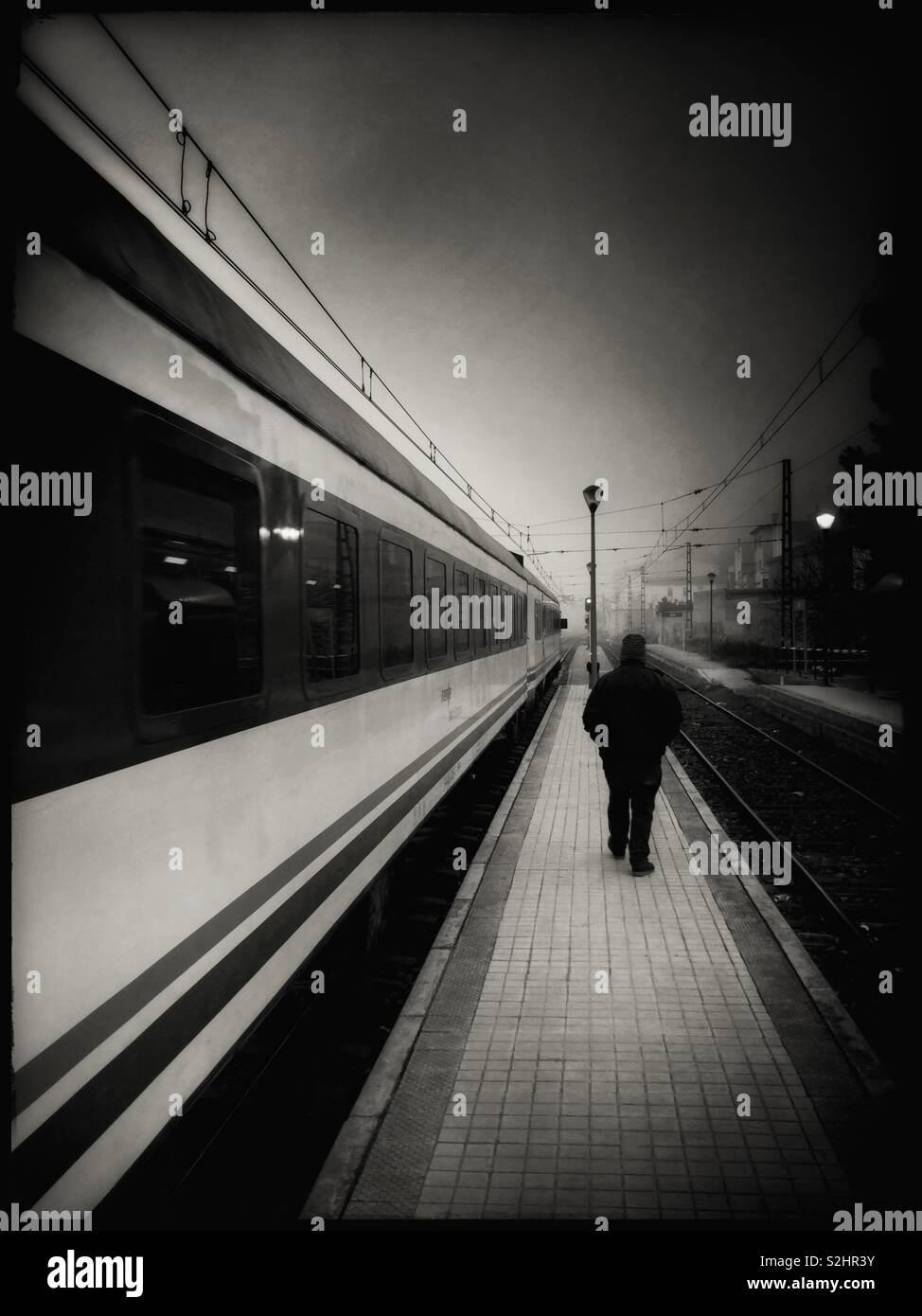 A train leaves the station at Ascó as a man walks by, Catalonia, Spain. - Smartphone Captured Stock Image