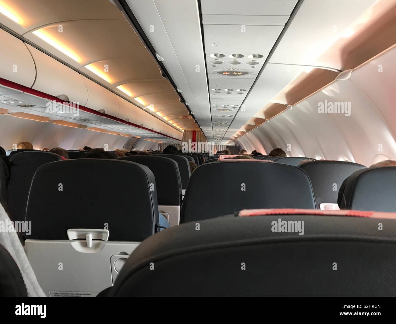 A point of view (POV) perspective from an economy class seat on a commercial airline aircraft is shown during a daytime flight. - Smartphone Captured Stock Image